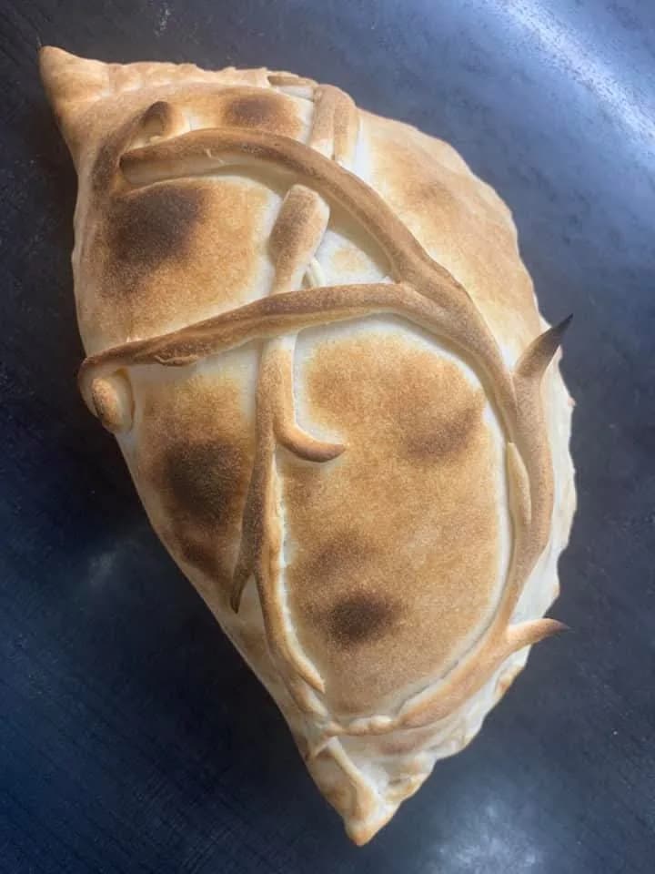 Bakad calzone hopfälld med utskuret deg-mönster och gyllenbrun yta — handgjord på Kärna Pizzeria