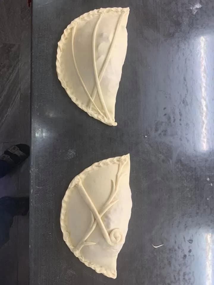 Två obakade calzoner med blad-mönster i degen, redo för ugnen — Kärna Pizzeria